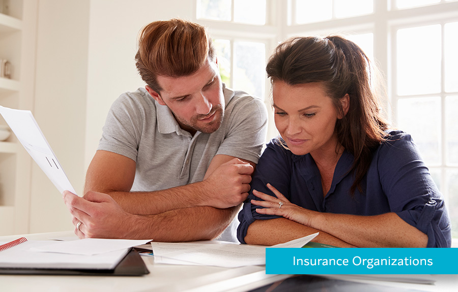 Couple looking at bills at home how Hyperwallet helps Insurance Organizations