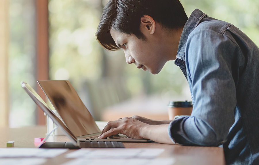 A male person reading on a laptop